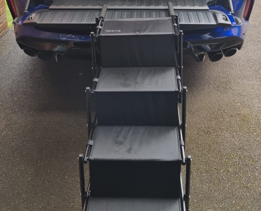This picture depicts the PiuPet fold-able dog steps being used with a car boot, so that a dog can climb up, without damaging their bones and joints.